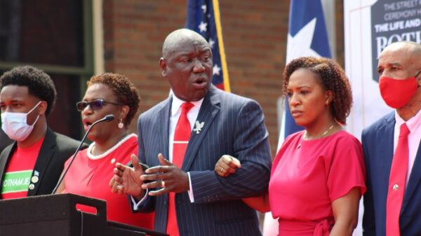 Attorney Benjamin Crump locks arms with Jean Family and leads crowd in chant - Do Mo to Be Like Bo
