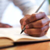 man writing in book