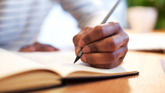 man writing in book