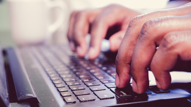 African American typing on laptop