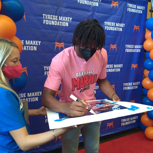 Tyrese Maxey singing a poster that was made for him by a fan, Mason Carvalho