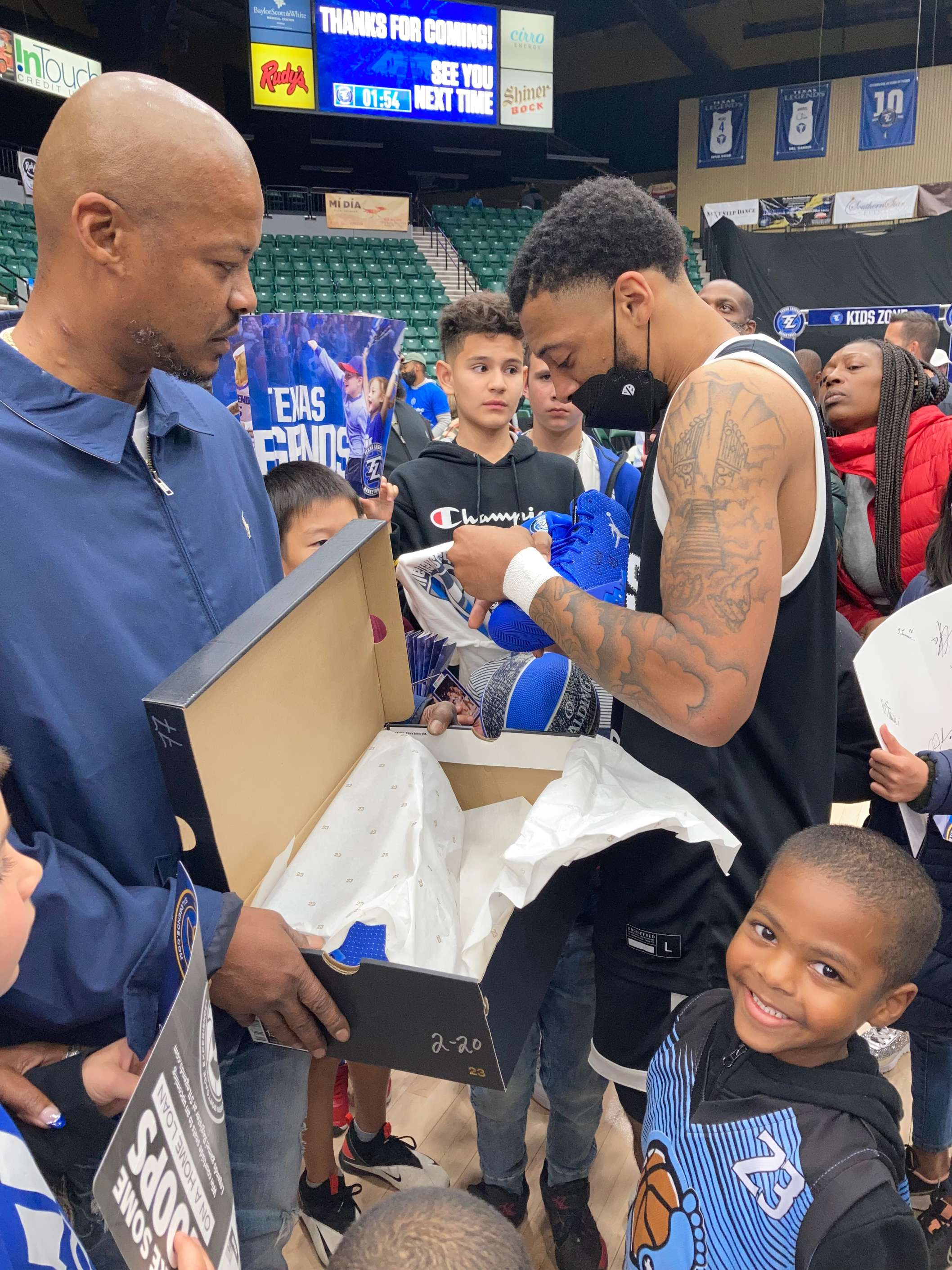 Texas Legends player giving a pair of his shoes to a young fan at a game.