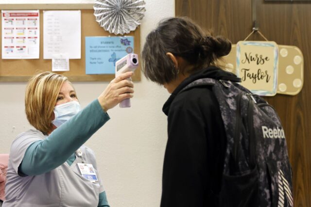 Stephanie Taylor checks a student’s temperatur