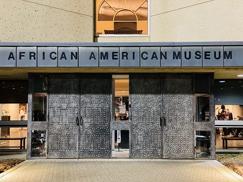 African American Museum exterior doors with Rob Holbert playing saxophone inside during Music Unde