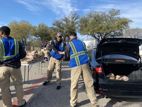 Police officers stack food boxes into car trunks 