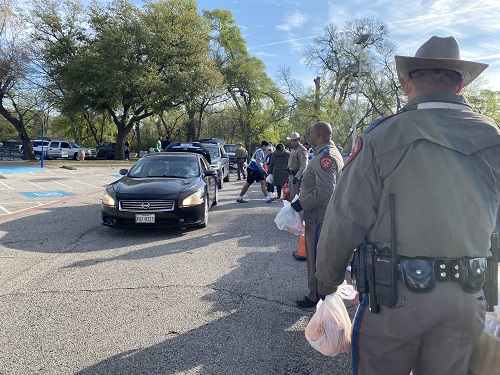 Volunteers load food boxes into cars lined up outside the Mark Cuban Heroes Basketball Center