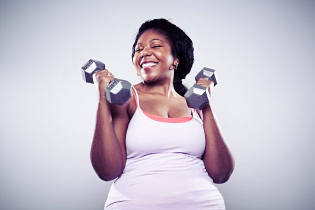 Mature woman using hand weights, smiling