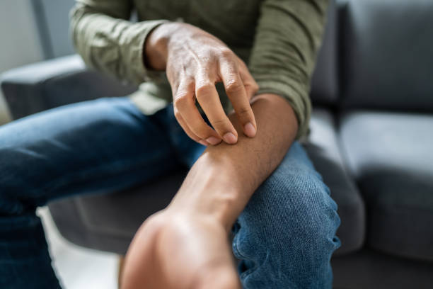 Midsection View Of A Man Sitting On Sofa Suffering From Itching