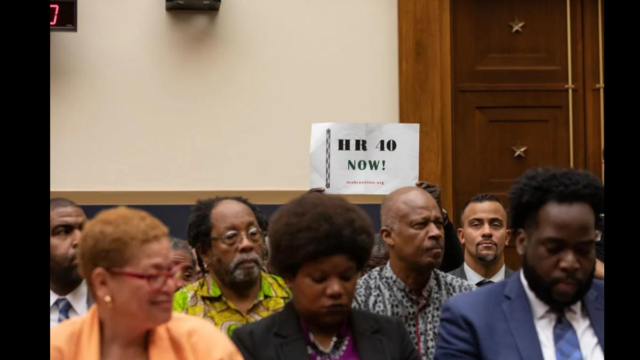 An attendee holds up a sign in support of HR 40