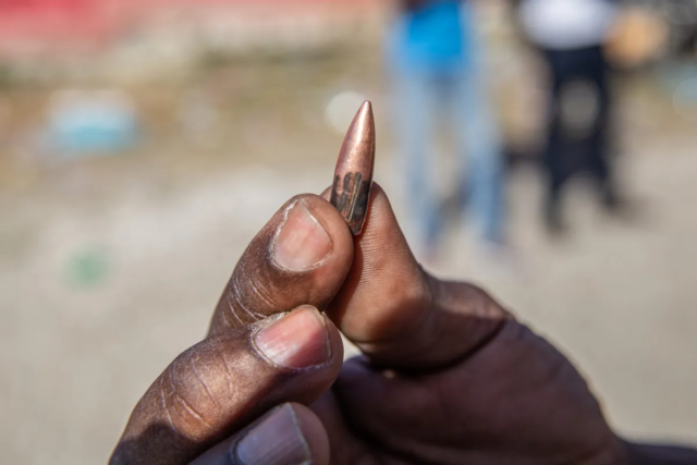 A-resident-who-fled-Plaine-du-Cul-de-Sac-holding-a-shell-from-a-lost-bullet-found-after-armed-gangs-attacked-the-area-on-Feb.-12.-Photo-credit-by-Guerinault-Louis-for-the-Haitian-Times-scaled