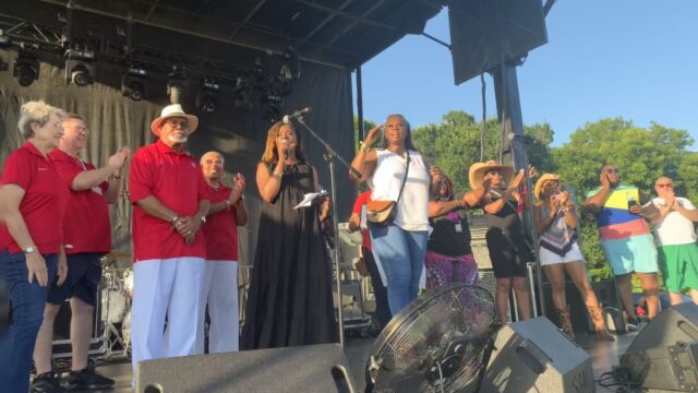 A Big Best Southwest display of unity on the Fourth. Lancaster Mayor Clyde C. Hairston (third from left with hat and crossed hands), DeSoto Mayor Rachel L. Proctor at the microphone, and Glenn Heights Mayor Sonja A. Brown salutes. DeSoto’s new City Manager, Majed Al-Ghafry is on the far right in green shorts.