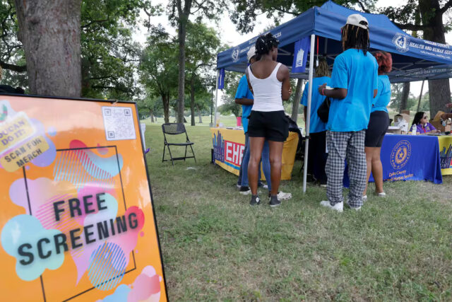 People gather around a registration tent 